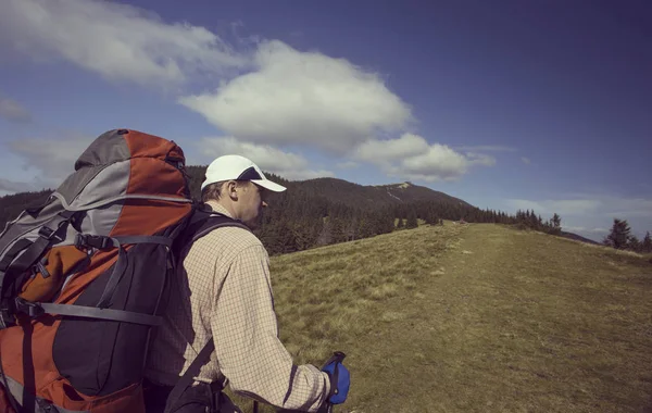 Hombre turista caminando por las montañas con una mochila . — Foto de Stock