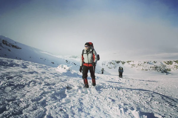 Caminhadas de inverno nas montanhas em sapatos de neve com uma mochila e — Fotografia de Stock