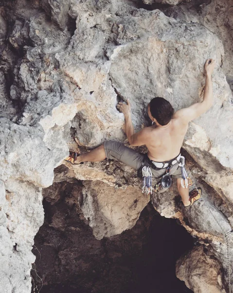Bergsteiger.Junger Mann klettert an einer Kalksteinwand mit breitem Tal im Hintergrund — Stockfoto