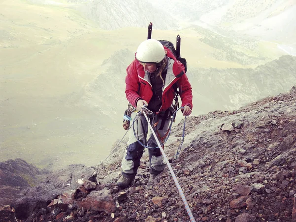 Escalador de rocas.Joven escalando en una pared de piedra caliza con amplio valle en el fondo — Foto de Stock