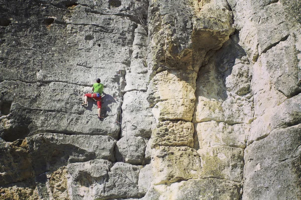 Rock Climber.Young man klimmen op een muur van kalksteen met grote vallei op de achtergrond — Stockfoto