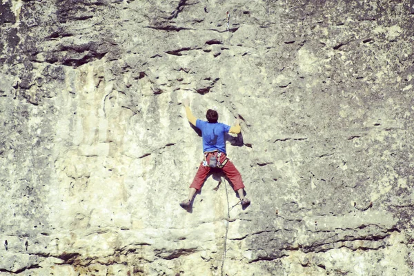 Escalador de rocas.Joven escalando en una pared de piedra caliza con amplio valle en el fondo — Foto de Stock