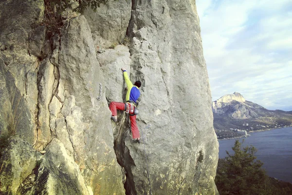 Escalador de rocas.Joven escalando en una pared de piedra caliza con amplio valle en el fondo — Foto de Stock