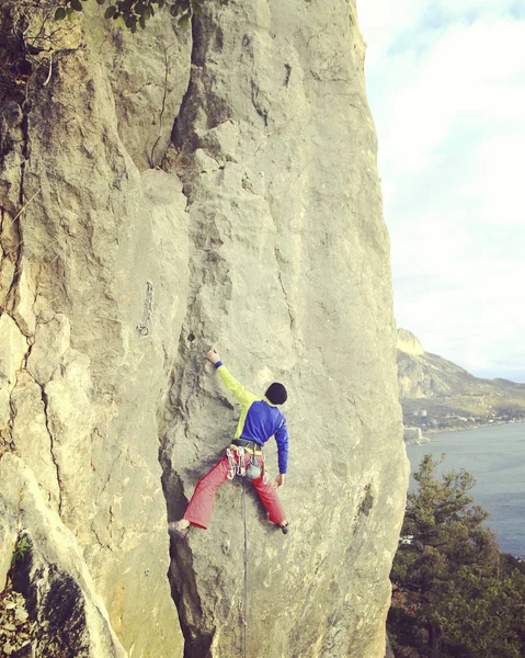 Escalador de rocas.Joven escalando en una pared de piedra caliza con amplio valle en el fondo — Foto de Stock