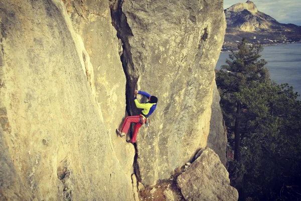 Escalador de rocas.Joven escalando en una pared de piedra caliza con amplio valle en el fondo — Foto de Stock