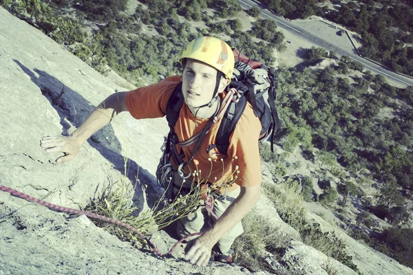 Escalador de rocas.Joven escalando en una pared de piedra caliza con amplio valle en el fondo —  Fotos de Stock