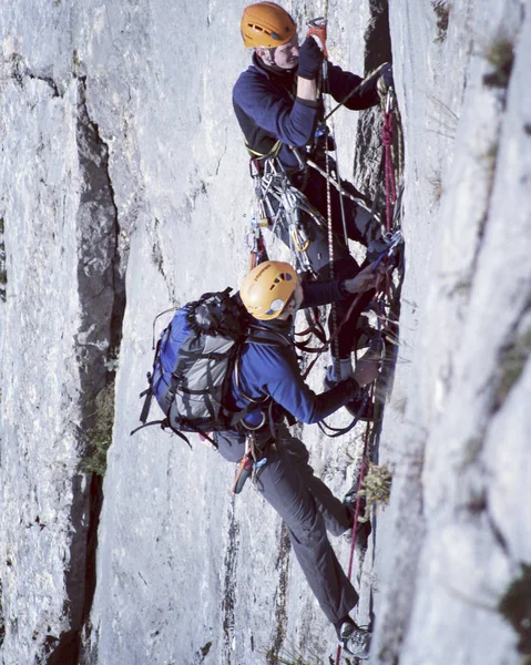Escalador de rocas.Joven escalando en una pared de piedra caliza con amplio valle en el fondo — Foto de Stock