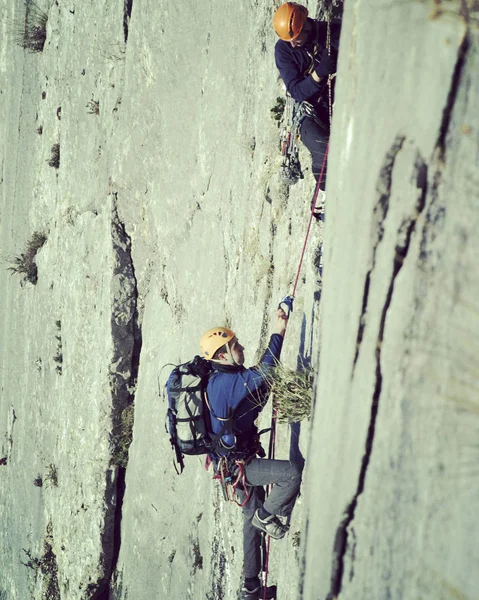 Escalador de rocas.Joven escalando en una pared de piedra caliza con amplio valle en el fondo — Foto de Stock