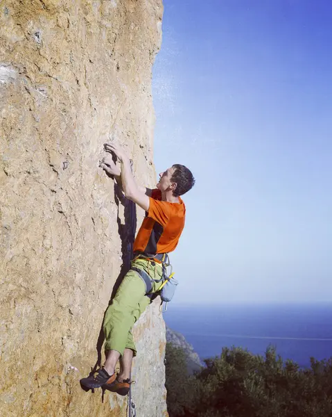 Escalada.Jovem escalando em uma parede de pedra calcária com amplo vale no fundo — Fotografia de Stock