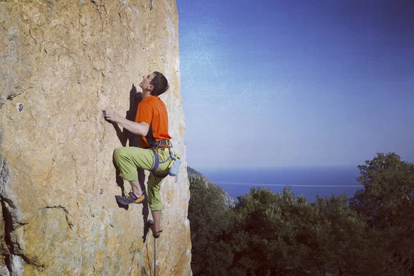 Escalada.Jovem escalando em uma parede de pedra calcária com amplo vale no fundo — Fotografia de Stock