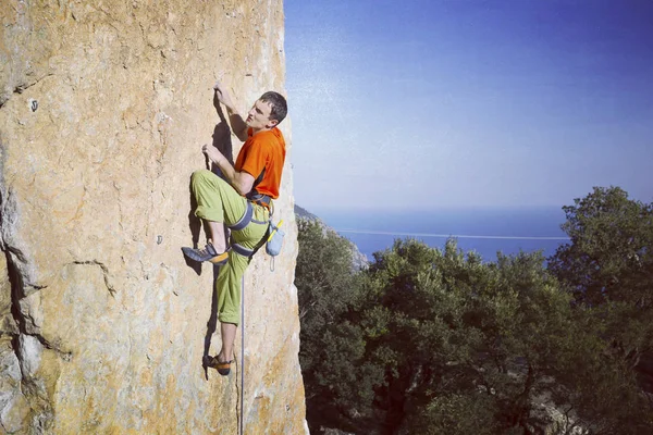 Rock Climber.Young mannen klättring på en kalksten vägg med brett dal på bakgrunden — Stockfoto