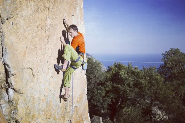 Rock Climber.Young mannen klättring på en kalksten vägg med brett dal på bakgrunden — Stockfoto