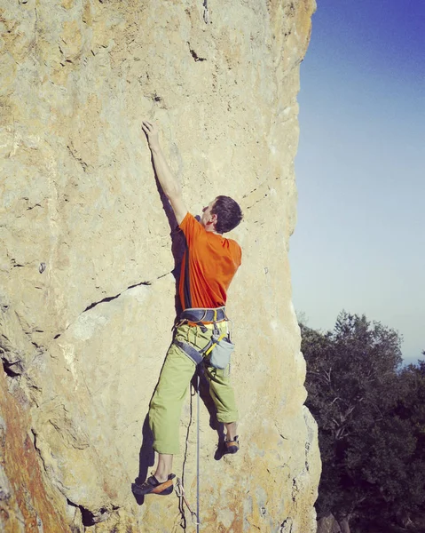 Bergsteiger.Junger Mann klettert an einer Kalksteinwand mit breitem Tal im Hintergrund — Stockfoto