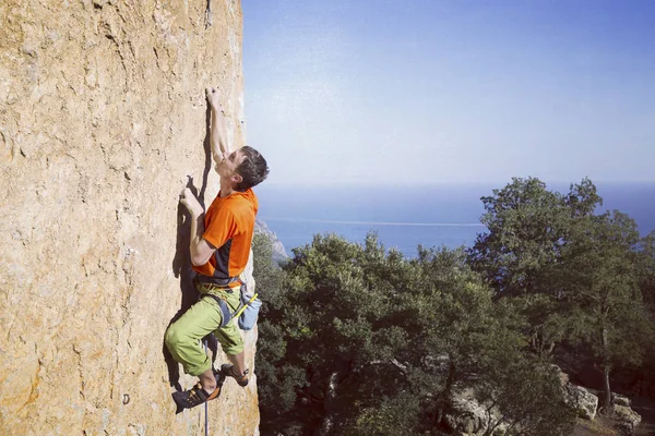 Rock Climber.Young człowiek wspinaczka na ścianie wapienia z szerokiej dolinie na tle — Zdjęcie stockowe