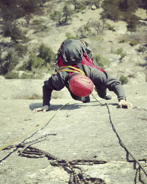 Escalador de rocas.Joven escalando en una pared de piedra caliza con amplio valle en el fondo — Foto de Stock