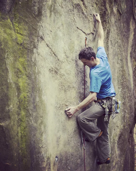 Rock Climber.Young man klimmen op een muur van kalksteen met grote vallei op de achtergrond — Stockfoto