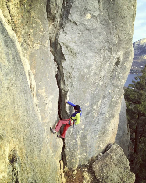 Escalador de rocas.Joven escalando en una pared de piedra caliza con amplio valle en el fondo — Foto de Stock