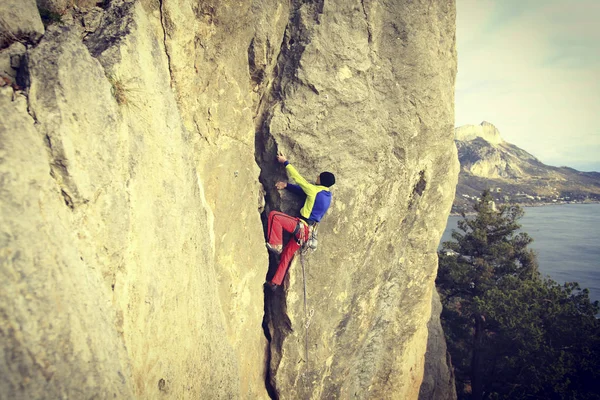 Rock Climber.Young man climbing on a limestone wall with wide valley on the background — Stock Photo, Image