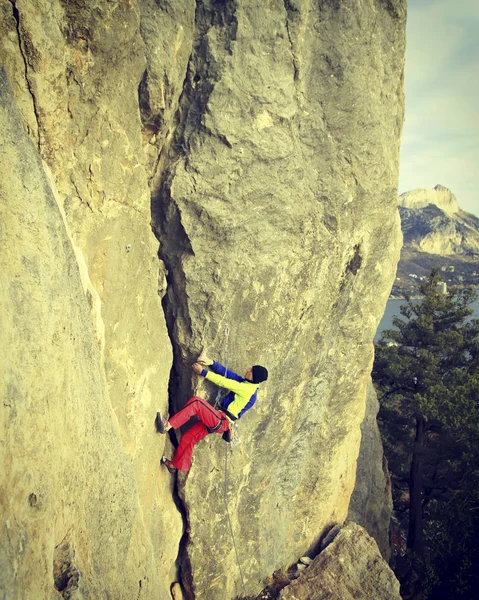 Arrampicata su roccia Giovane arrampicata su una parete calcarea con ampia valle sullo sfondo — Foto Stock