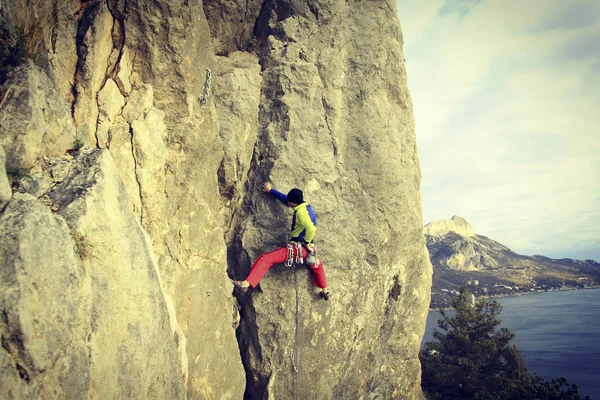 Rock Climber.Young man klimmen op een muur van kalksteen met grote vallei op de achtergrond — Stockfoto