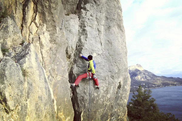 Escalade.Jeune homme grimpant sur un mur de calcaire avec une large vallée sur le fond — Photo