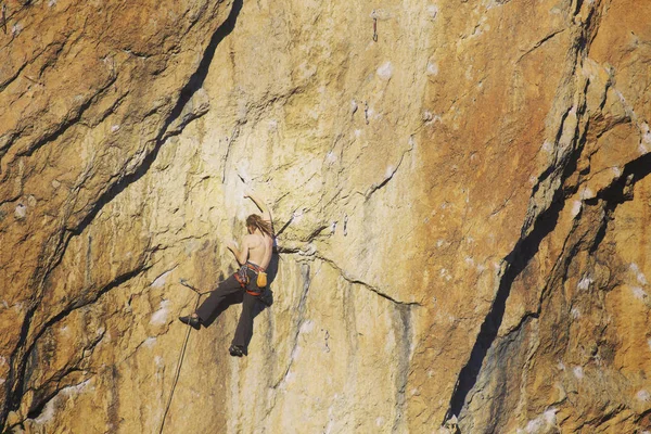 Скалолазание. Молодой человек взбирается на известняковую стену с широкой долиной на заднем плане — стоковое фото