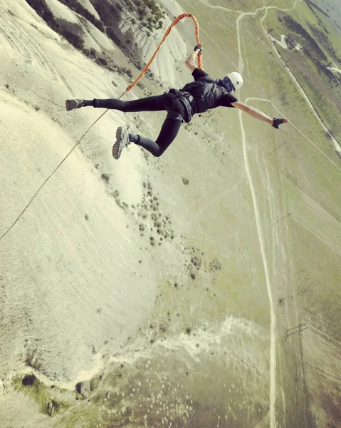 Rep hoppande. Hoppa från en klippa i en kanjon med ett rep. — Stockfoto