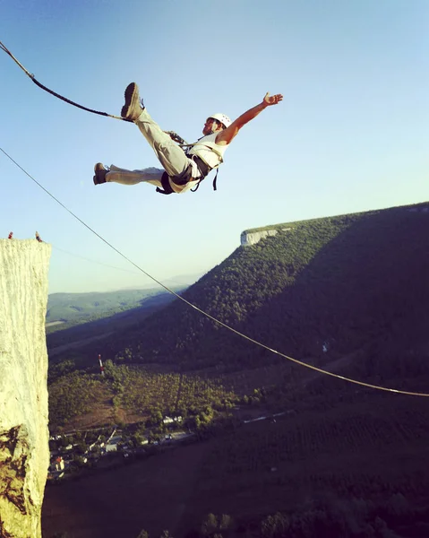 Прыжок с веревки. Прыжок со скалы в каньон с веревкой . — стоковое фото