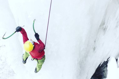 Buz tırmanışı. Adam buz aracıyla donmuş bir şelale.