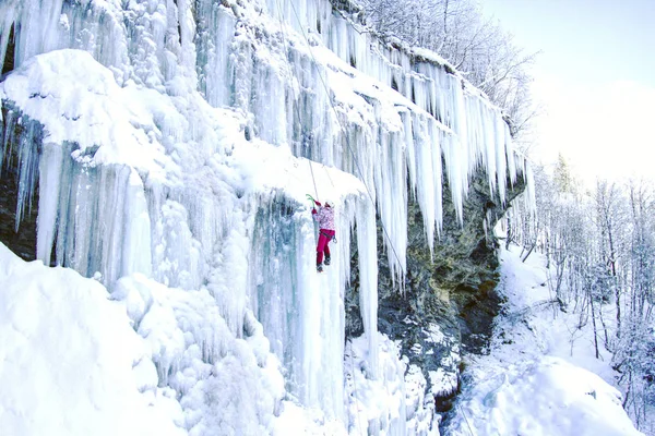 Arrampicata su ghiaccio.Uomo che scala una cascata ghiacciata con l'attrezzo del ghiaccio . — Foto Stock