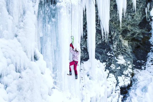 Arrampicata su ghiaccio.Uomo che scala una cascata ghiacciata con l'attrezzo del ghiaccio . — Foto Stock