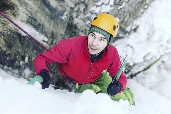 Eisklettern: Mann besteigt gefrorenen Wasserfall mit Eiswerkzeug. — Stockfoto