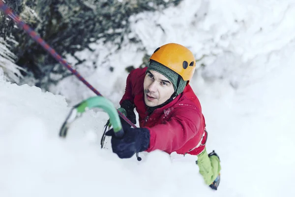 Eisklettern: Mann besteigt gefrorenen Wasserfall mit Eiswerkzeug. — Stockfoto