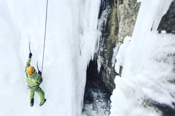 Arrampicata su ghiaccio.Uomo che scala una cascata ghiacciata con l'attrezzo del ghiaccio . — Foto Stock