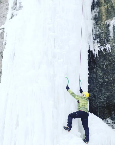 攀冰。男子爬冰工具与冰冻的瀑布. — 图库照片