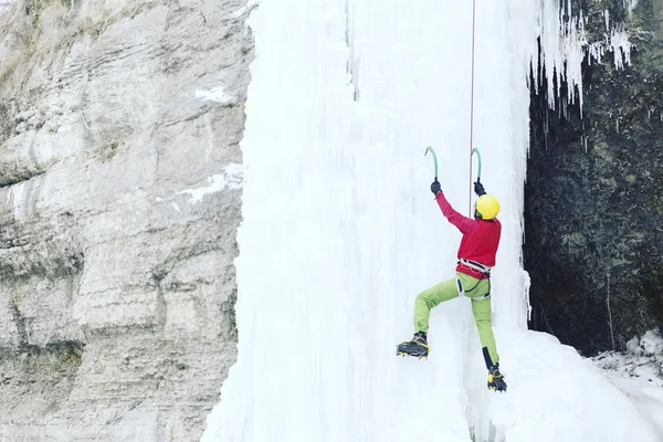 Ice climbing.Man climbing a frozen waterfall with ice tool. — Stock Photo, Image