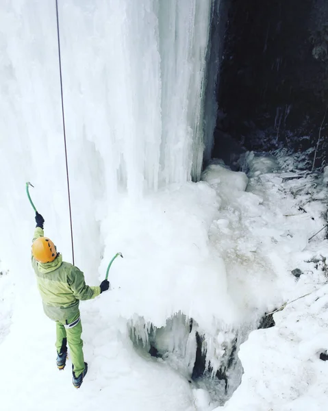 Wspinaczka po lodzie. Człowiek, wspinaczka po zamarzniętym wodospadzie narzędziem lodu. — Zdjęcie stockowe