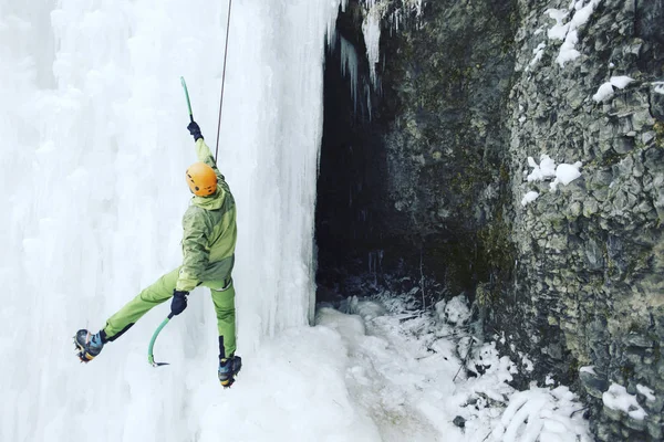 Eisklettern: Mann besteigt gefrorenen Wasserfall mit Eiswerkzeug. — Stockfoto