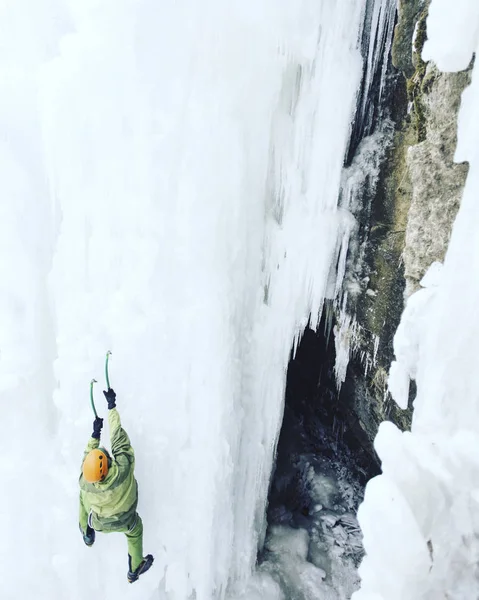 Ice climbing.Man climbing a frozen waterfall with ice tool.