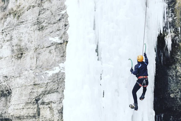 Jég mászás. Férfi hegymászó egy fagyasztott vízesés ice eszközzel. — Stock Fotó