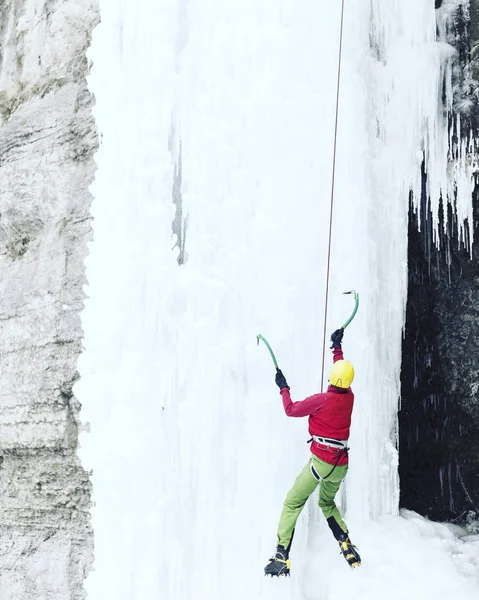攀冰。男子爬冰工具与冰冻的瀑布. — 图库照片