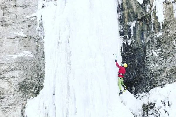 Eisklettern: Mann besteigt gefrorenen Wasserfall mit Eiswerkzeug. — Stockfoto