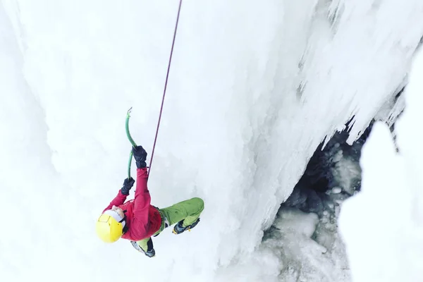 Escalada de hielo.Hombre escalando una cascada congelada con herramienta de hielo . —  Fotos de Stock
