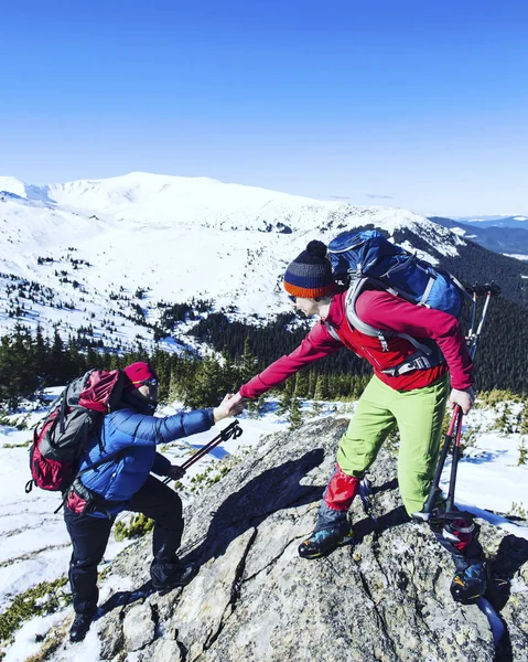 Чоловік дає допомогу подрузі, щоб піднятися на скелі гірських порід . — стокове фото