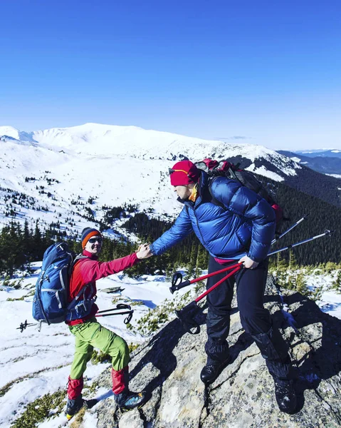 Hombre dando ayuda mano a amigo para escalar montaña roca acantilado . — Foto de Stock