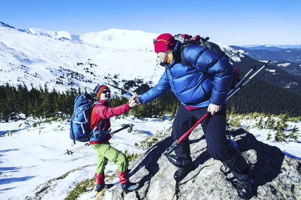 Hombre dando ayuda mano a amigo para escalar montaña roca acantilado . — Foto de Stock