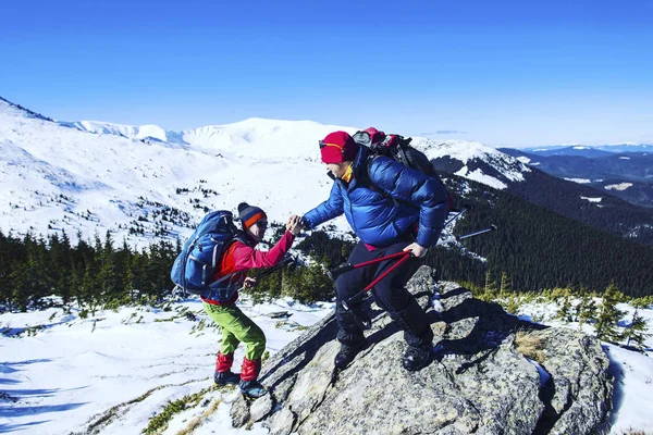 Man helpende hand geven naar vriend te beklimmen berg rots rots. — Stockfoto