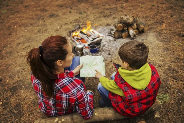 Кемпінг в лісі. Мама і син сидять біля вогню попередньо — стокове фото