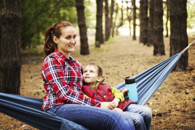 Ormanda kamp. Anne ve oğlu bir hamakta oturmuş ve 