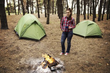Ormanda kamp. Kız bir hamakta oturur ve t görünüyor